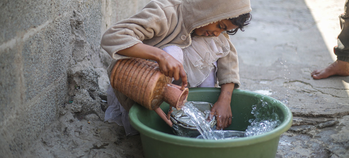 A displaced child washes dishes in an IDP camp in Yemen after the water supply was recently restored.