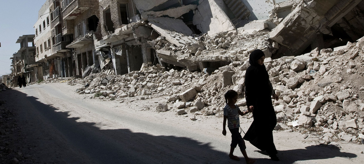 A young girl and a woman walk past destroyed buildings in the city of Maarat al-Numaan in Idlib, Syria.
