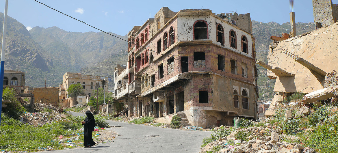 A woman walks in Taiz, a war-ravaged city in Yemen, split by a frontline.