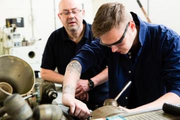 An apprentice in a workshop receiving training advice from a senior employee © EU