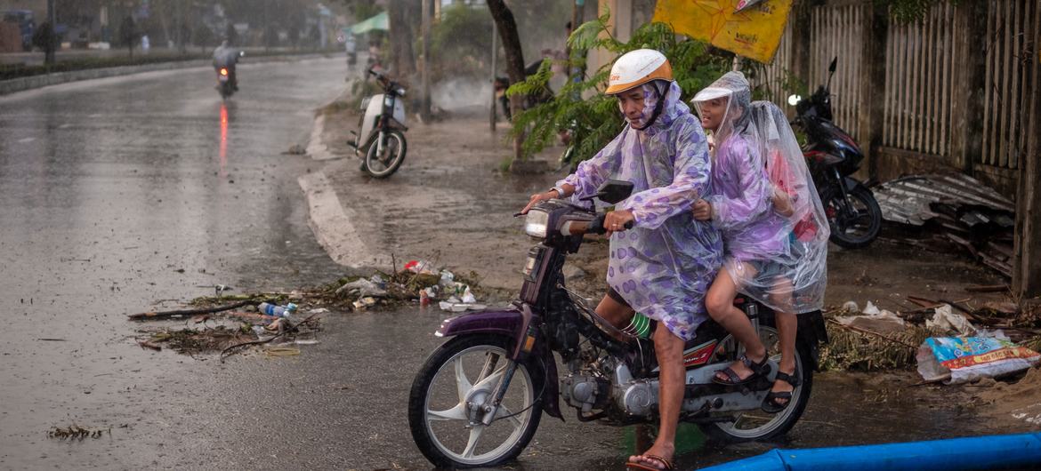 A man carries his children on motorbike passing through the flooded road in Da Nang City, Vietnam on October 30, 2020, in the aftermath of Typhoon Molave.