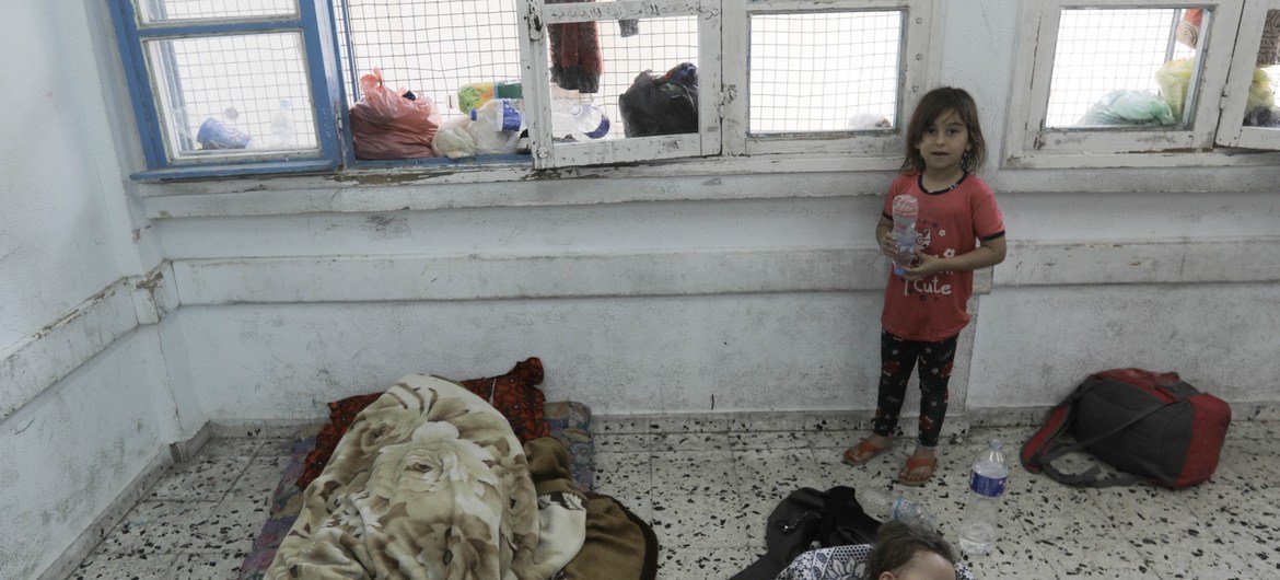 A young child watches over her toddler siblings sleeping in a classroom of UNRWA Salah Eddin School in Gaza.