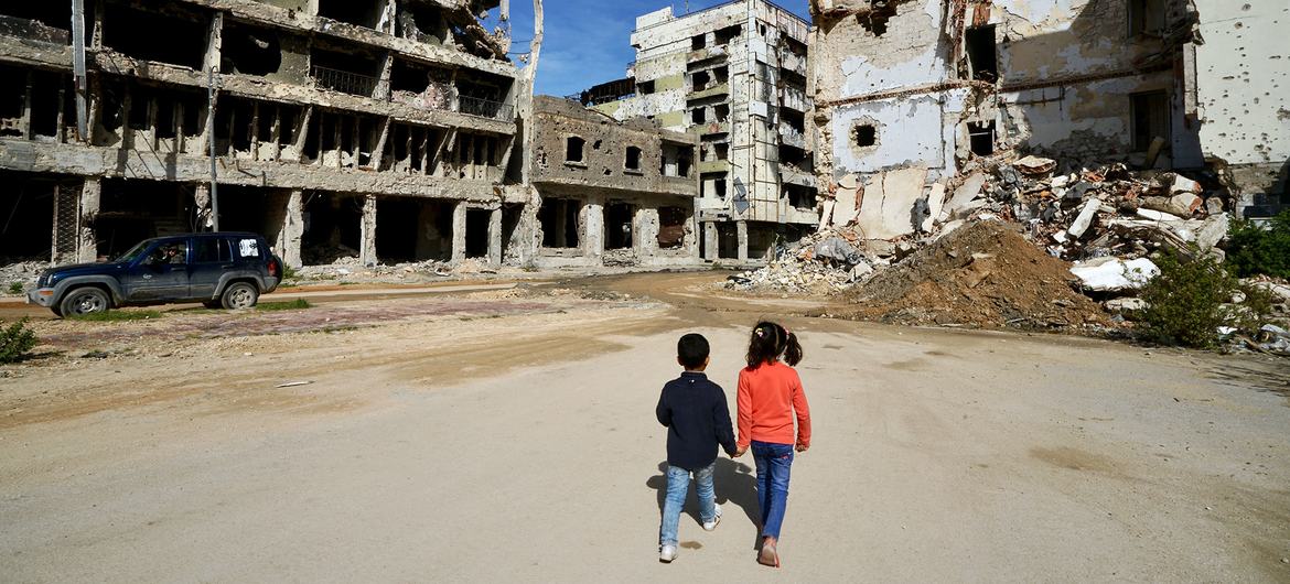 Children walk past damaged buildings in Benghazi in Libya.