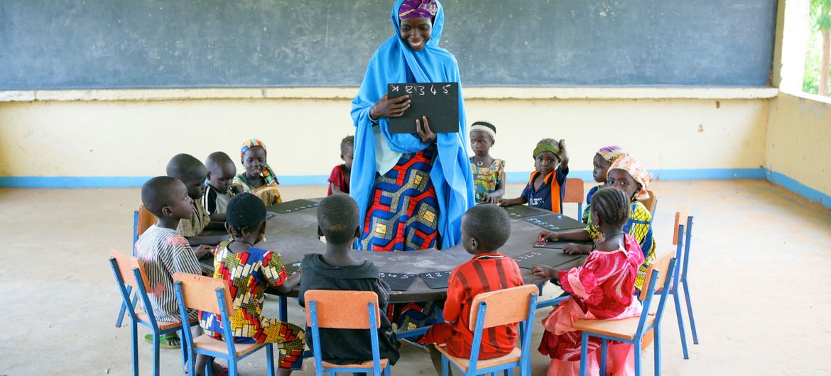 Children sit in a circle with their teacher at the Early Child Development centre in Garin Badjini village, south east Nigeria.
