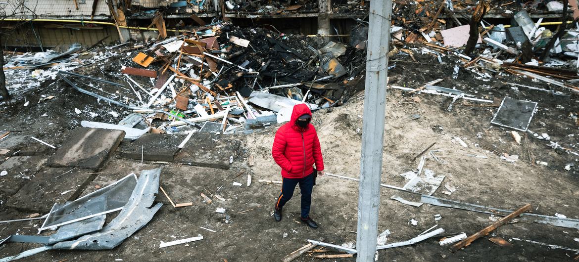 A man walks in front of a crater left by an explosion during escalating conflict in Kyiv, Ukraine. 