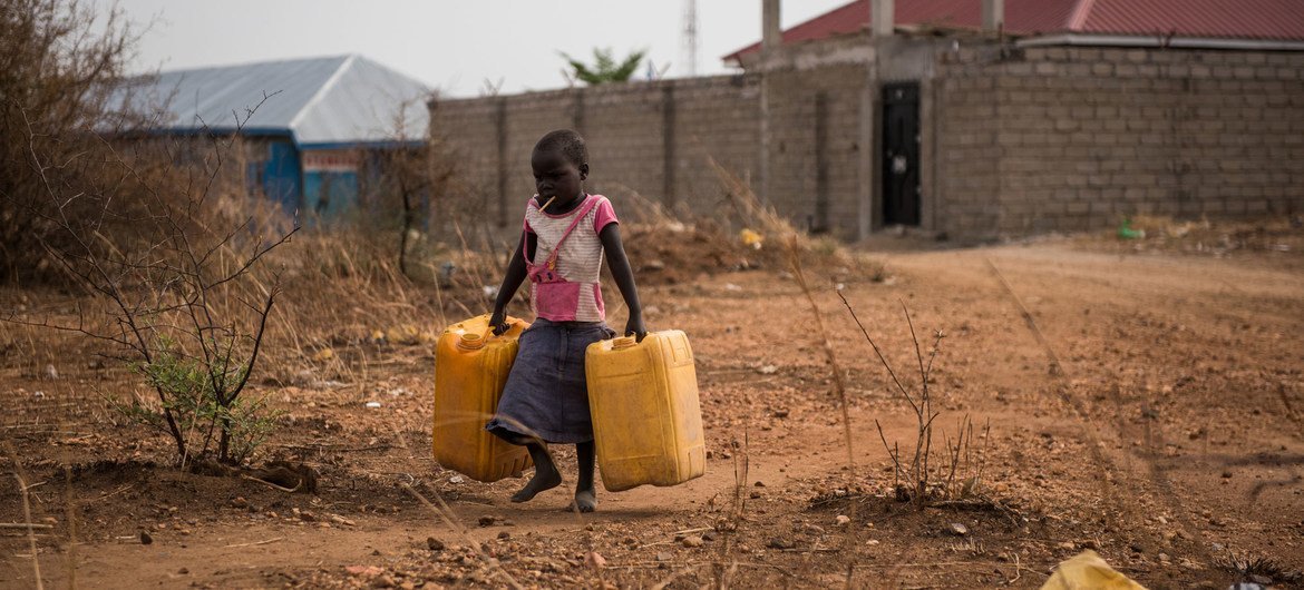 A child carries empty jerry cans to fill with water from a nearby tap providing untreated water from the Nile river in Juba, South Sudan.