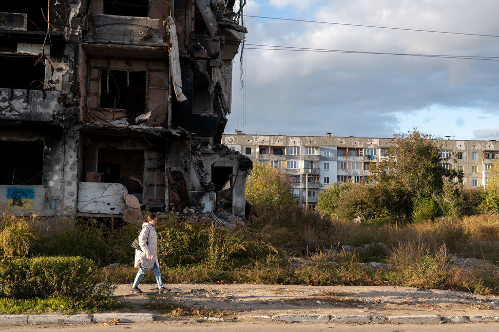 A woman walks past a destroyed apartment block in western Ukraine.