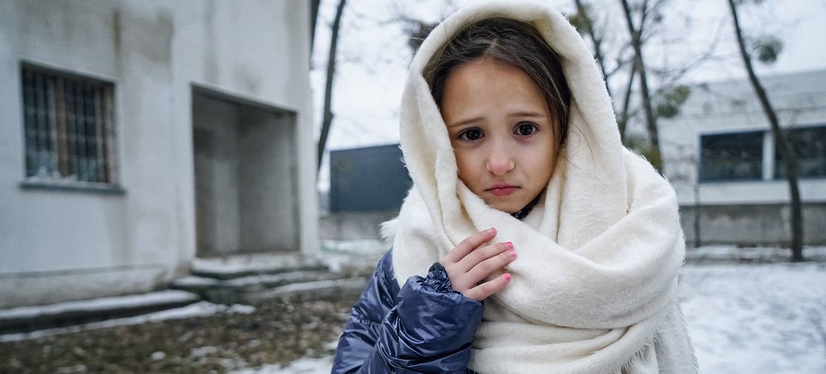 An 8-year-old girl poses in front of a building in Irpin, Ukraine where her mother and sister share a small room.