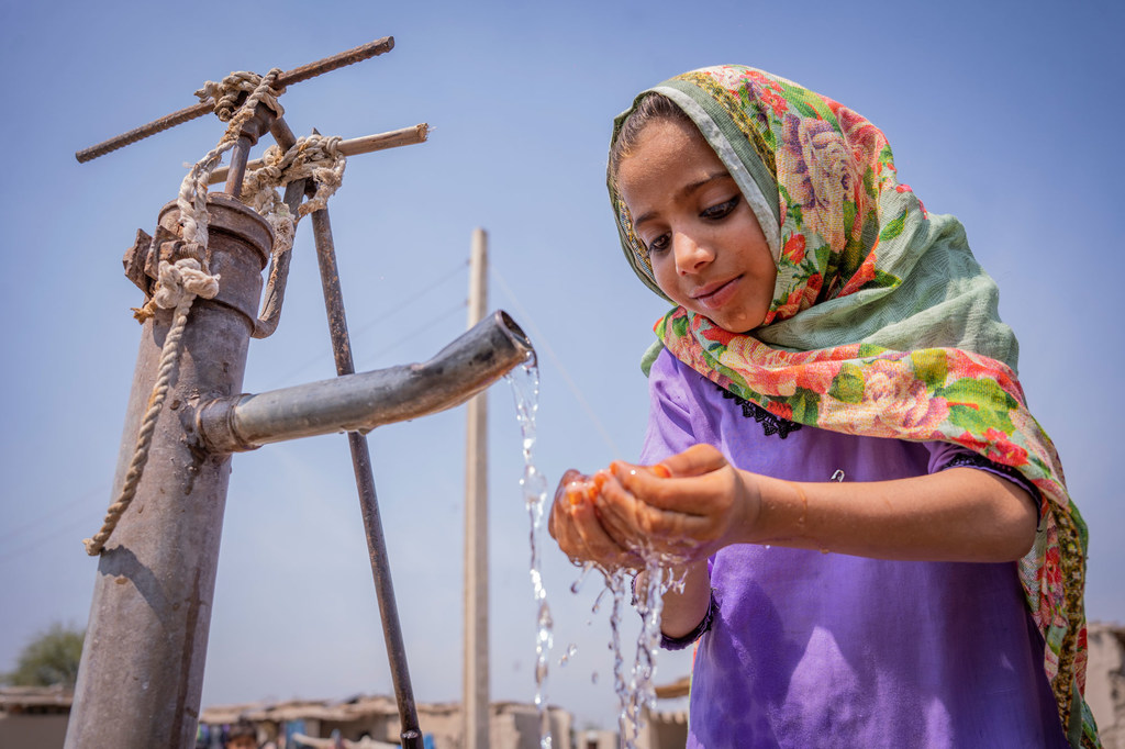 A six-year-old girl drinks water from a community hand pump in Pakistan.