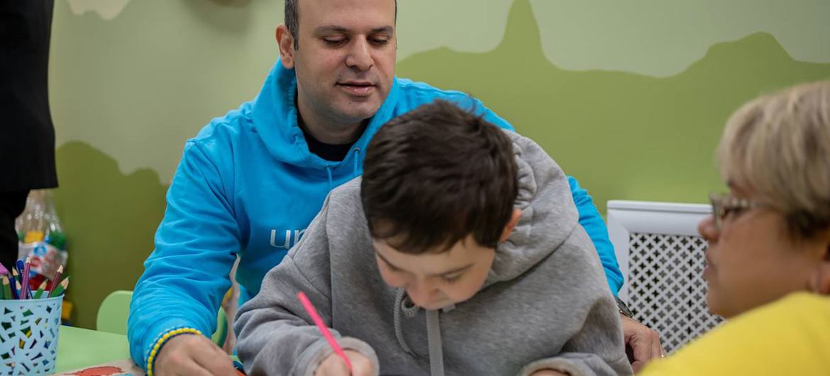 Munir Mammadzade sits with a young Ukrainian in a UNICEF-supported facility.